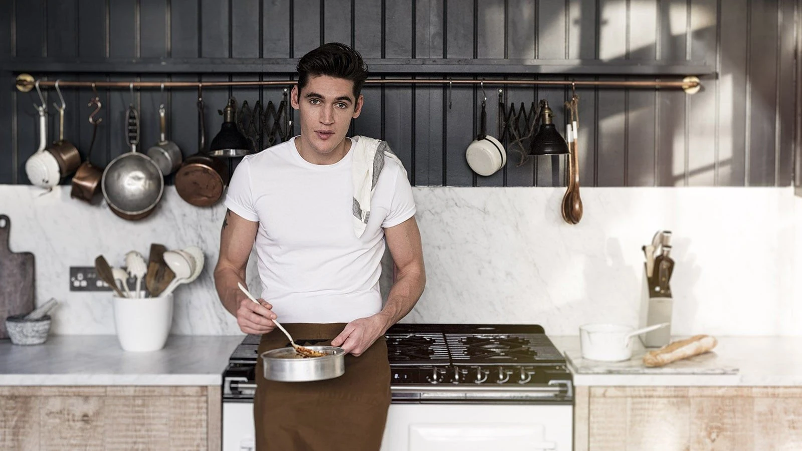 Isaac Carew at the hob, stirring a pan of fresh pasta on a black AGA range.